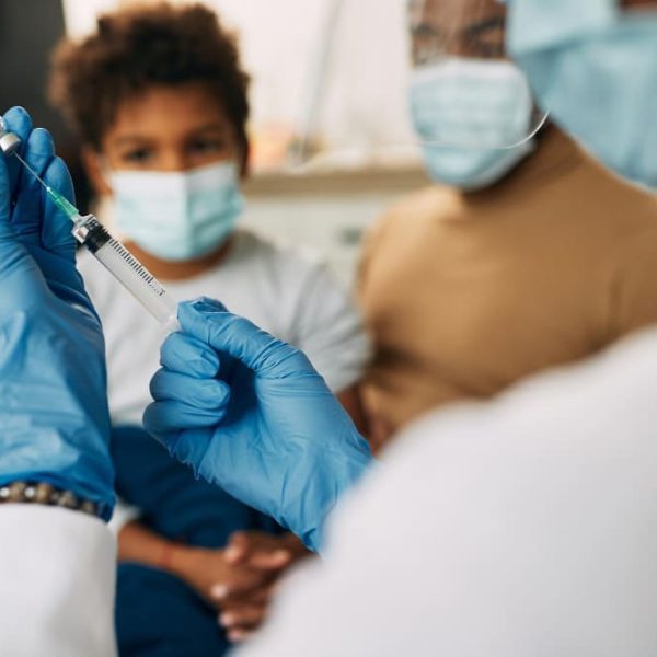 Un docteur qui va vacciner un enfant.